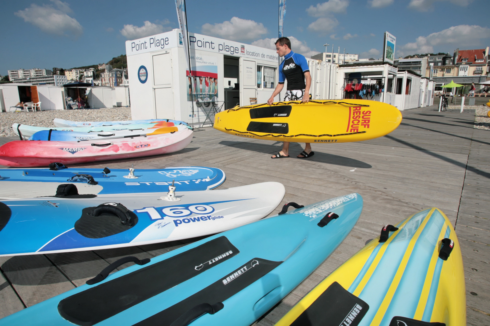 Un homme dispose des canoë devant le Point Plage