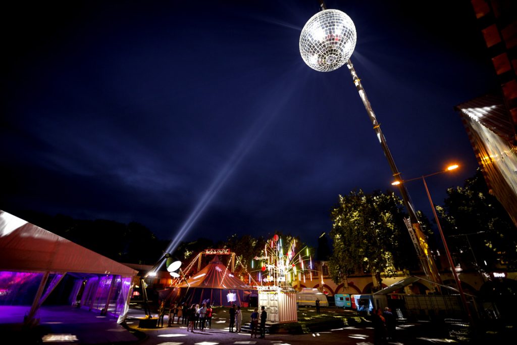 Ouest Park Festival, extérieur avec une boule à facettes géante, un chapiteau, et un arbre illuminé