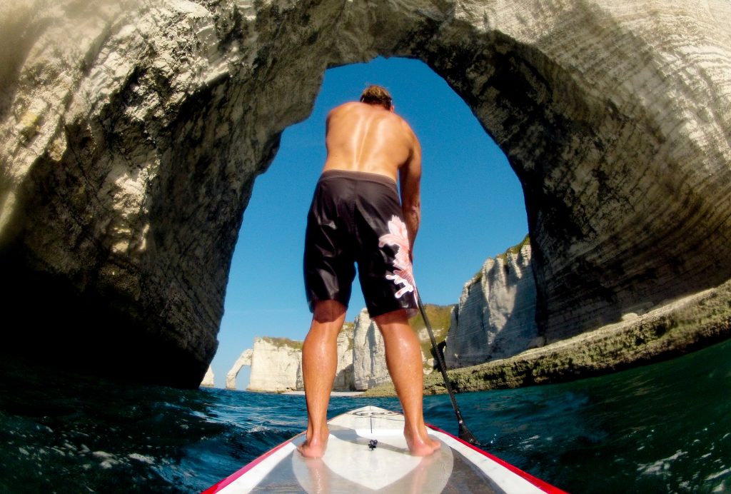 Homme sur un paddle sous l'arche d'Etretat