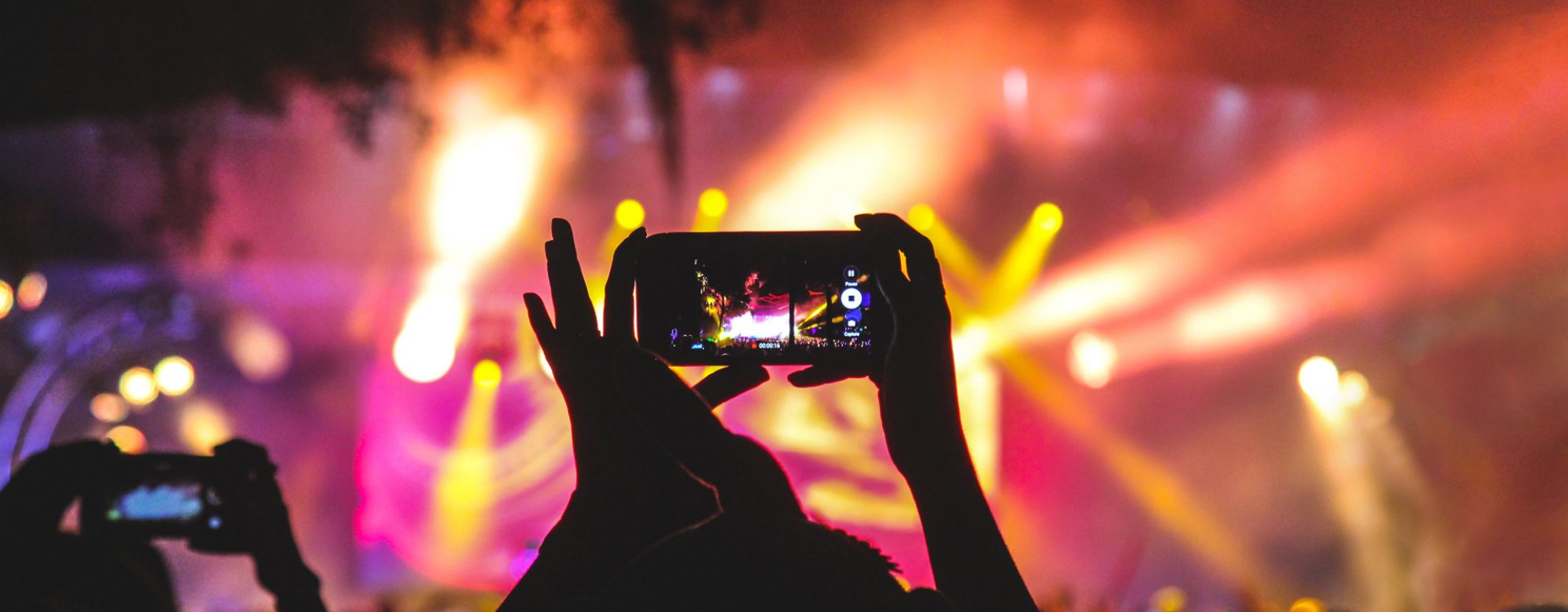 Personne utilisant son smartphone pour filmer un spectacle de nuit en extérieur